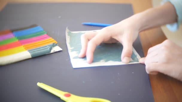 A menina sentada à mesa, desenha figuras diferentes da plasticina de modelo a cores. Desenvolvimento de modelagem de arte em crianças. 4k, close-up — Vídeo de Stock