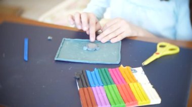 masada oturan kız farklı renk model hamuru rakamları çizer. Çocuklarda modelleme sanat kalkınma. 4k, yakın çekim