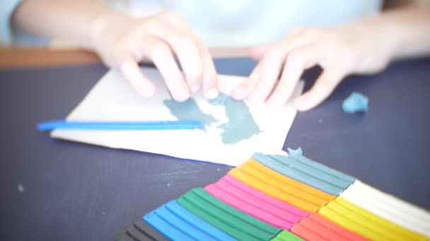 A menina sentada à mesa, desenha figuras diferentes da plasticina de modelo a cores. Desenvolvimento de modelagem de arte em crianças. 4k, close-up — Vídeo de Stock