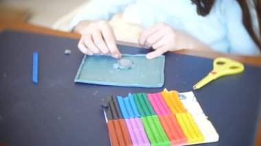 masada oturan kız farklı renk model hamuru rakamları çizer. Çocuklarda modelleme sanat kalkınma. 4k, yakın çekim