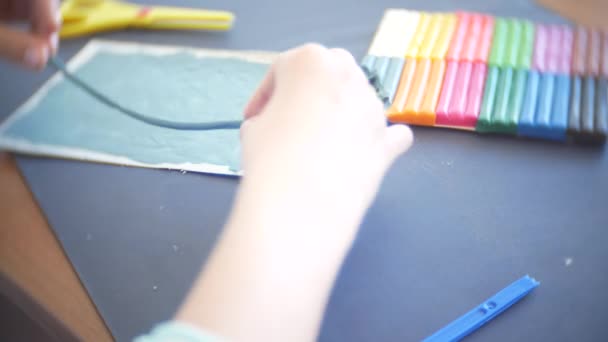 Девушка, сидящая за столом, рисует разные фигуры из пластилина цветовой модели. Развитие художественного моделирования у детей. 4k, крупный план — стоковое видео