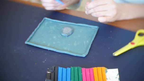 A menina sentada à mesa, desenha figuras diferentes da plasticina de modelo a cores. Desenvolvimento de modelagem de arte em crianças. 4k, close-up — Vídeo de Stock