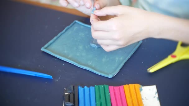 A menina sentada à mesa, desenha figuras diferentes da plasticina de modelo a cores. Desenvolvimento de modelagem de arte em crianças. 4k, close-up — Vídeo de Stock