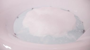 İnsan olmadan sabun köpüğü ile köpüren su ile dolu bir jakuzi ile modern bir yuvarlak banyo. 4k, ağır çekim