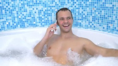 Genç bir adam banyo yaparken suya bir cep telefonu düşürür.