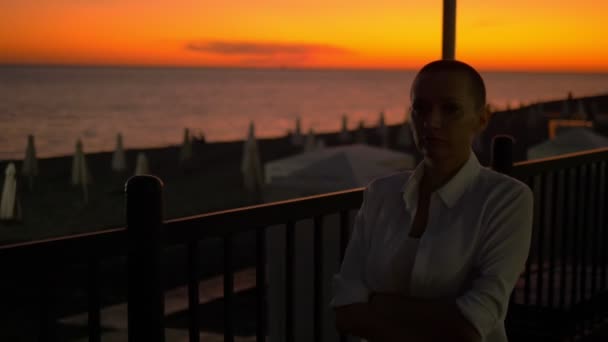 Silhouette of a young bald woman on a sunset promenade background — Stock Video