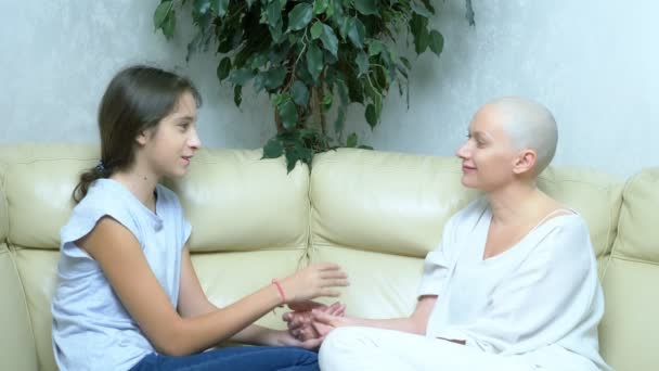Vacker skallig kvinna kommunicerar med sin dotter på soffan i vardagsrummet — Stockvideo