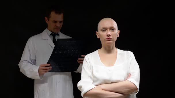 概念腫瘍患者、はげの女性と医師の男性は黒い背景に断層撮影の結果を表示しています. — ストック動画
