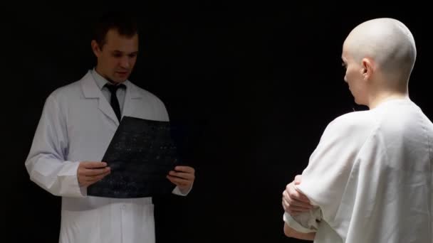 Konzept onkologischer Patient, glatzköpfige Frau und Arzt betrachten Tomographie-Ergebnisse auf schwarzem Hintergrund. — Stockvideo