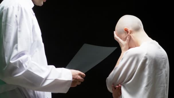 Concept Oncological patient, bald woman and doctor man are viewing tomography results on black background. — Stock Video