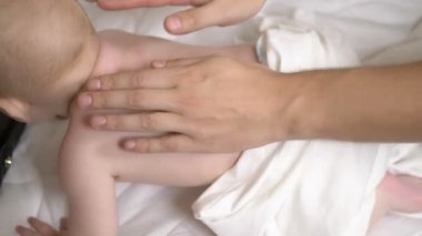 Erkeklerin elleri bir bebeğin sırtına masaj yapar.