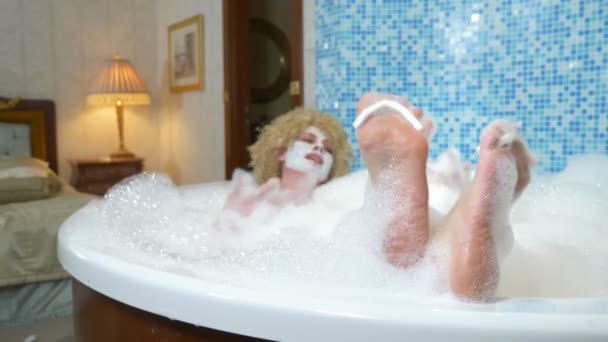 Gros plan. womans pieds avec séparateurs de doigts sont recouverts de mousse de bain. femme faisant pédicure prendre un bain de mousse — Video