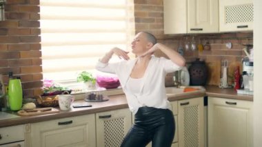Orta boy. Genç, inanılmaz duygusal, kel kadın evdeki mutfakta dans ediyor.