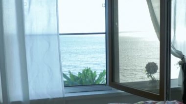Denize bakan penceredeki şeffaf perde, rüzgarla hafifçe hareket etti. Güneş ışığı.
