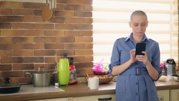 Середній постріл. стильна лисиця використовує мобільний телефон на кухні вдома — стокове відео
