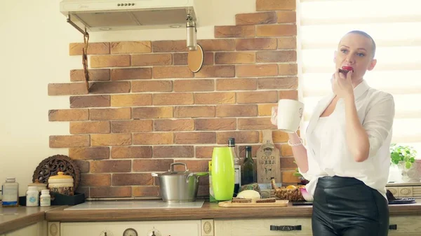 Medium shot. Stylish bald woman drinking a hot drink while standing in the kitchen at home. — Stock Photo, Image