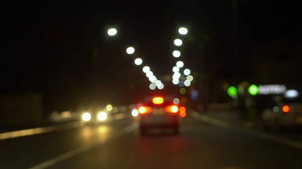 Розмитий фон. вид з вікна автомобіля з розмитим освітленням міського руху на вулицях міста вночі — стокове фото