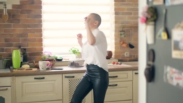 Tiro médio. jovem mulher careca incrivelmente emocional dançando na cozinha em casa — Vídeo de Stock