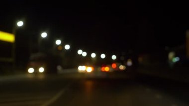 Arka plan bulanık. Şehir trafiğini bulanık aydınlatan gece vakti araba penceresinden manzara