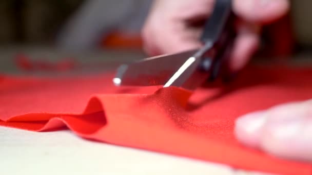 Mani maschili tagliano forbici tessuto rosso. il concetto di design e sartoria. super primo piano . — Video Stock