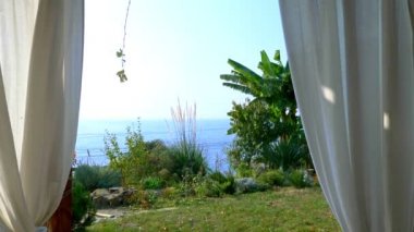 Çardaktaki beyaz perdeler. deniz, ufuk ve yeşil bitkiler