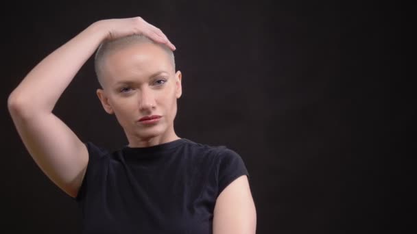 Blond woman with very short hair on black background looking at the camera. — Stock Video