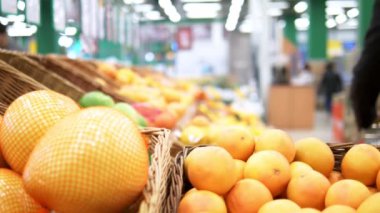 Süpermarkette tezgahın üzerinde turunçgiller. Bir adam portakal topluyor.