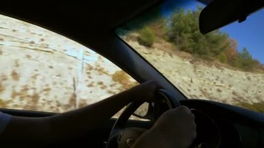 Yakın plan. Erkek el hareket eden bir arabanın direksiyonunda pencereden sonbahar manzarası tepeler ve mavi gökyüzü