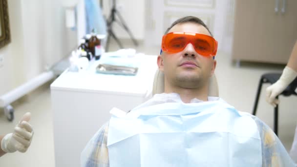 Пацієнт чоловік у стоматологічному кріслі. відвідування стоматолога — стокове відео