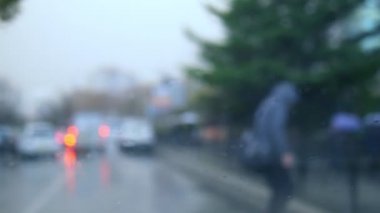 Yağmurda arabanın penceresinden manzara. Bir yaya karşıdan karşıya geçiyor.