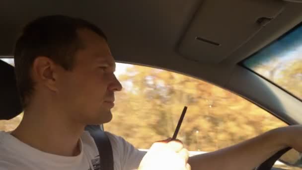 Мужчина курит электронную сигарету за рулем автомобиля — стоковое видео