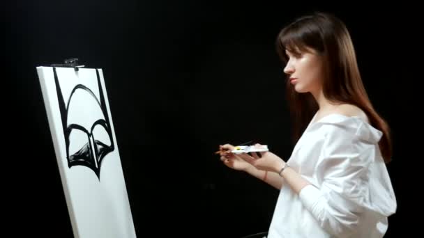 Piękna brunetka dziewczyna artysta maluje obraz na płótnie. czarne tło — Wideo stockowe