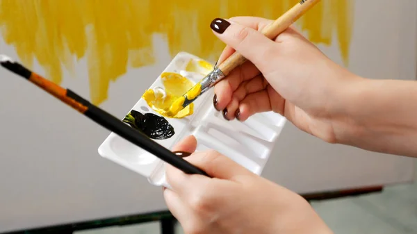 Closeup, the artist causes the oil paint on the canvas. black and yellow pattern — Stock Photo, Image