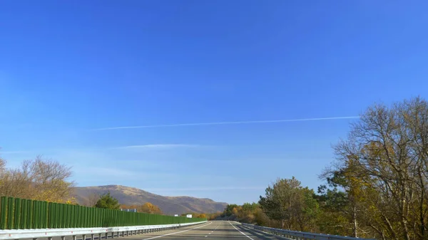 Blick aus der Windschutzscheibe eines Autos während der Fahrt. Leere Straße umgeben von Feldern — Stockfoto