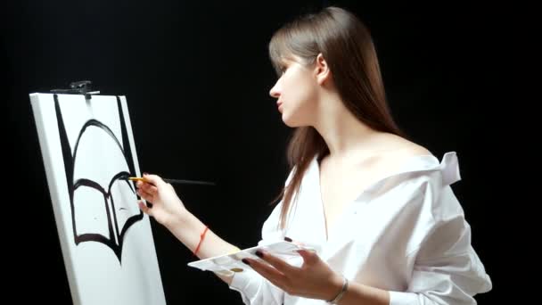 Женская рука с маникюром с кистью с черной краской на белом холсте — стоковое видео