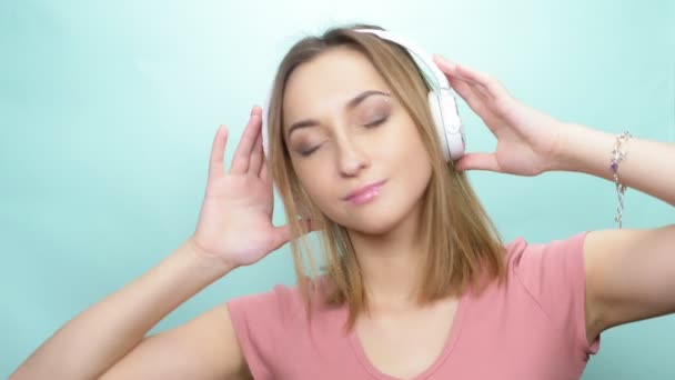 Menina com sobrancelha perfurada e olhos grandes com fones de ouvido em um fundo colorido — Vídeo de Stock