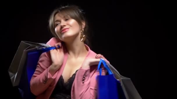 Элегантная молодая женщина с пакетами на черном фоне. торговые продажи — стоковое видео