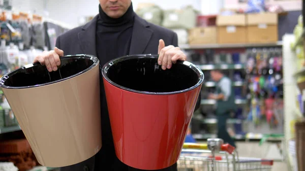 Jeune homme ramasse des pots de fleurs sur un comptoir dans un supermarché — Photo