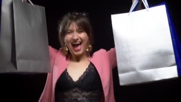 Elegante junge Frau mit Paketen auf schwarzem Hintergrund. Einkaufsgutscheine — Stockvideo