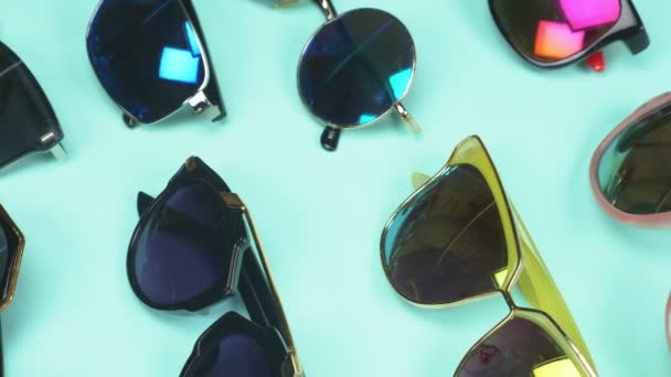 Набор солнцезащитных очков случайно лежащих на синем фоне. дизайн одежды — стоковое видео