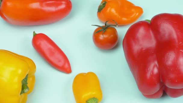 Pimentas doces pequenas e grandes e tomates cereja misturados em um fundo azul — Vídeo de Stock