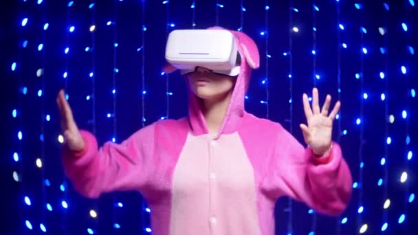 Fröhliches Mädchen im rosa Pyjama kigurumi in vr Gläser mit Girlanden — Stockvideo