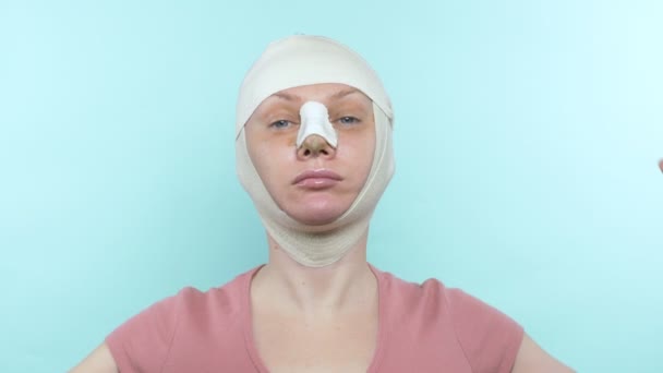 Woman after plastic surgery with bandage on face and nose. shows sign super — Stok video