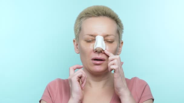 Žena s obvazem po plastice nosorožce se poškrábe na nose pod sádrou — Stock video