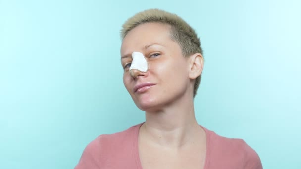 A woman with a bandage on her nose after rhinoplasty shows an ok sign — Stockvideo