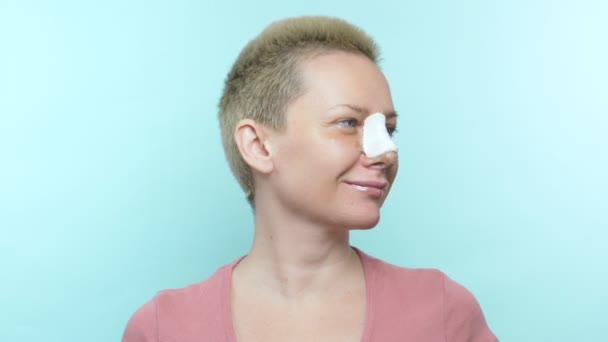 Жінка з пов'язкою на носі після ринопластики показує знак ок — стокове відео
