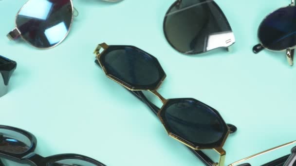 A set of sunglasses randomly lying on a blue background. fashion design — Stock Video