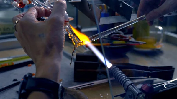 Fechar as mãos masculinas. fazer artesanato de vidro por derretimento de vidro em um queimador — Fotografia de Stock