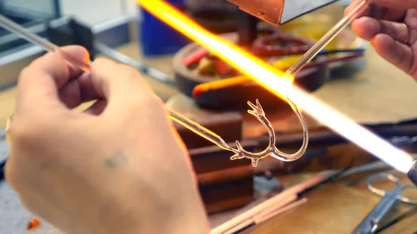 Primer plano de las manos masculinas. hacer artesanías de vidrio por fusión de vidrio en un quemador — Foto de Stock