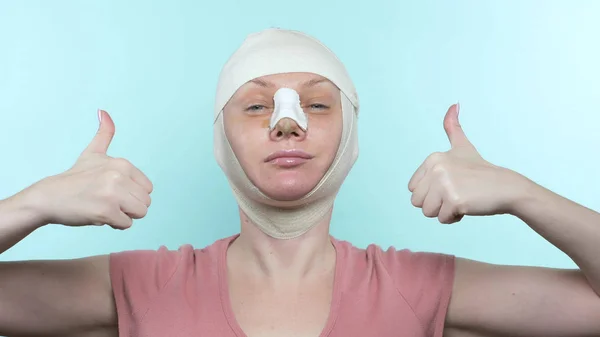 Frau nach Schönheitsoperation mit Verband im Gesicht und an der Nase. Zeigt Zeichen super — Stockfoto